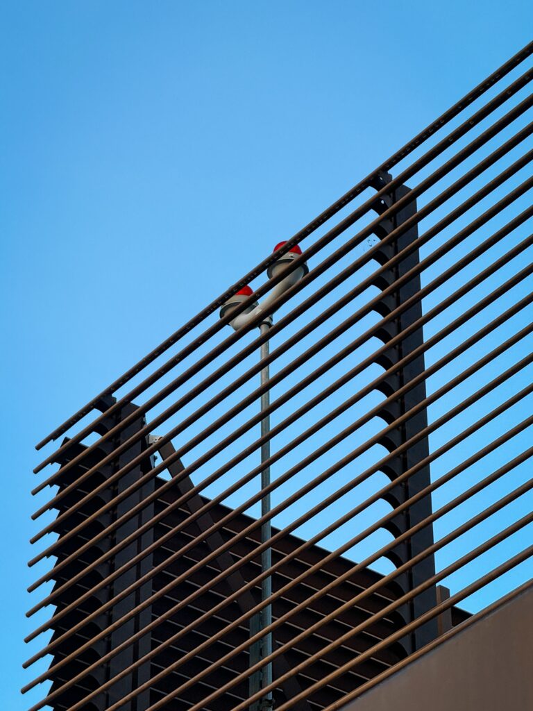 Modern black aluminum fence against blue sky