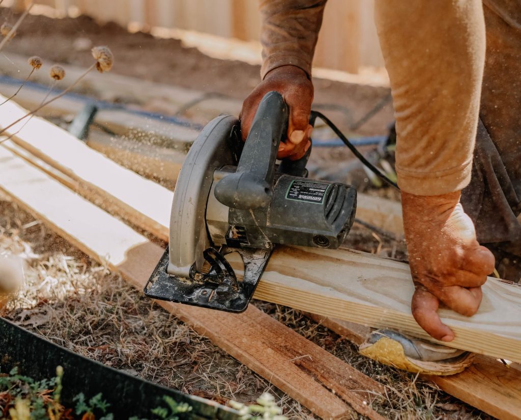 Fence contractor cutting wood during installation